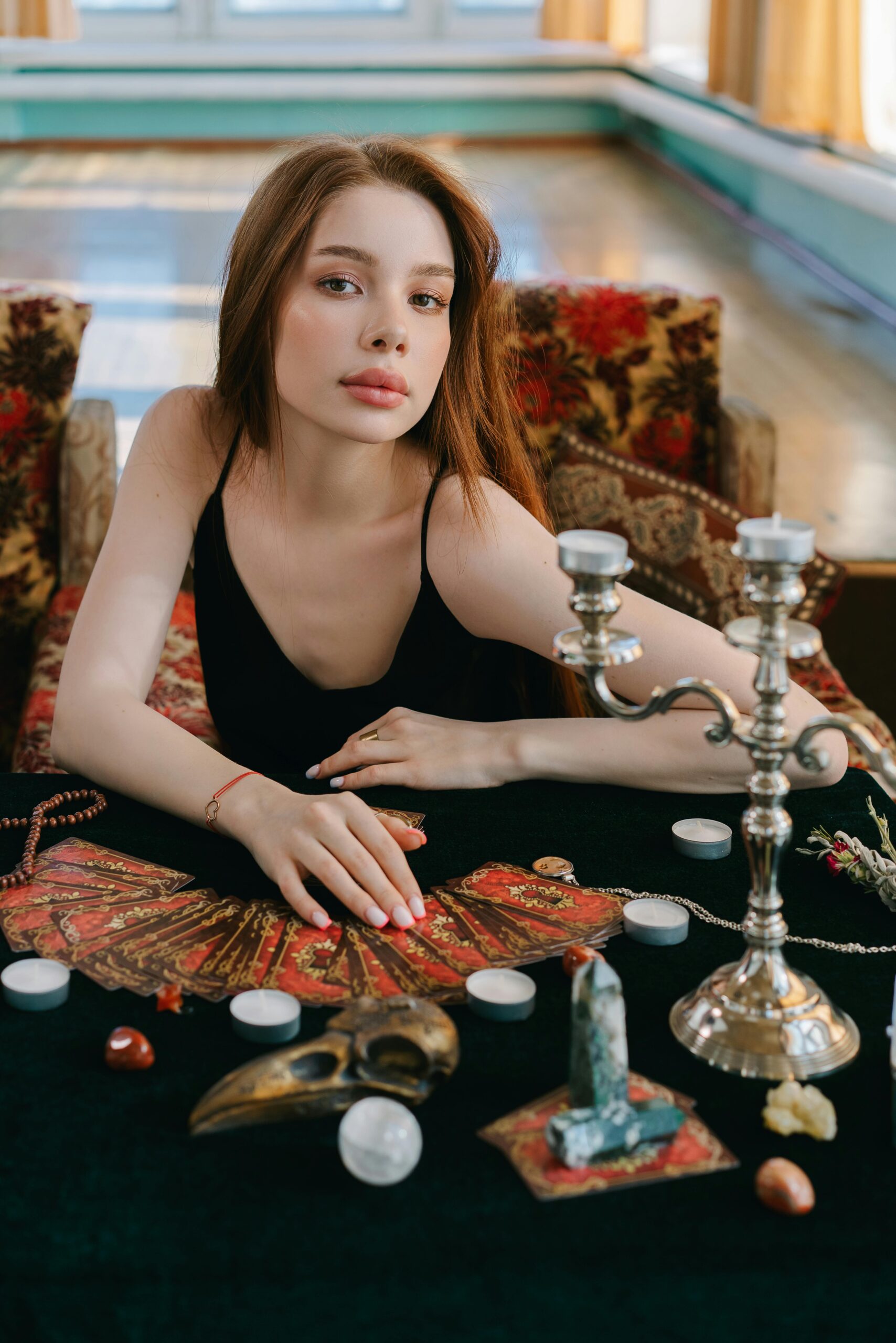 Calm woman with tarot cards and crystals, exuding a mystical aura indoors.